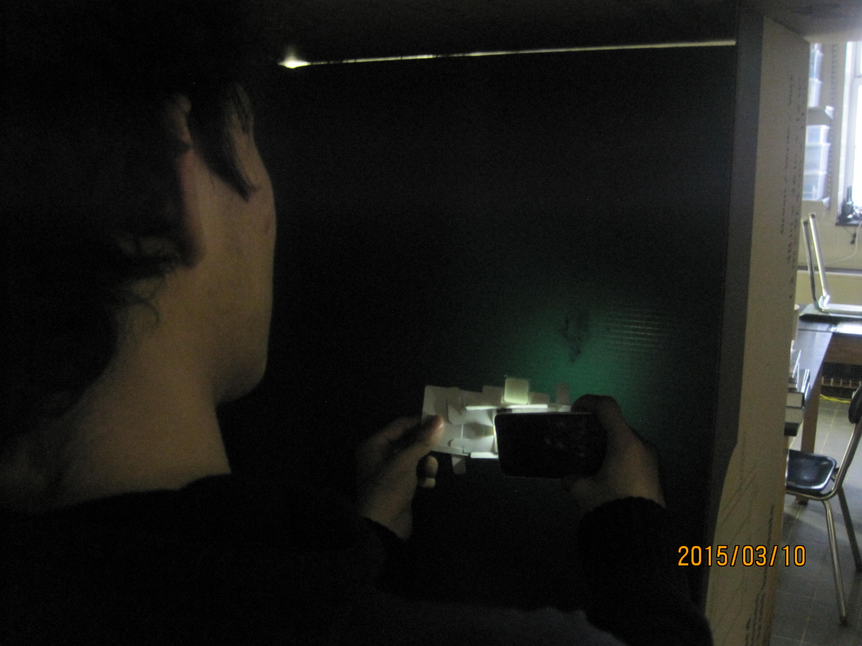 Jose Projecting an Amoeba on to a dark wall.
